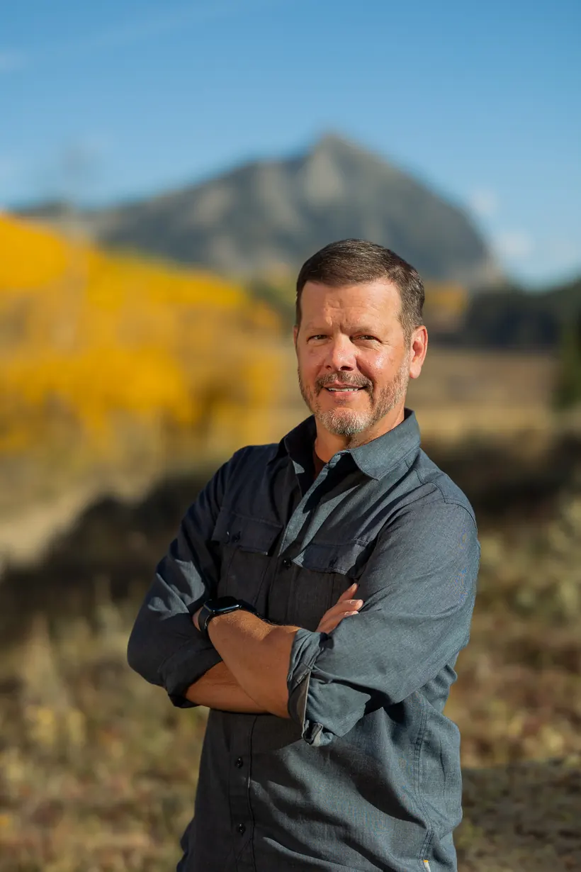 Bill Fournet, arms crossed, in the Colorado mountains