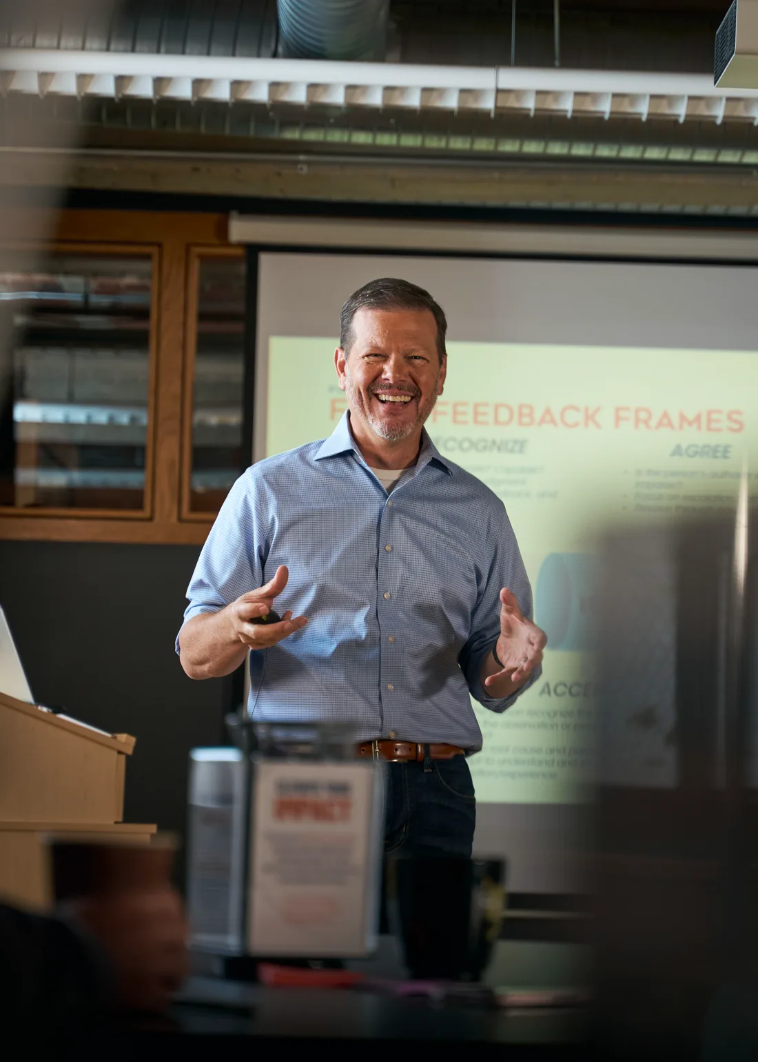 Bill Fournet laughing as he leads an in-house session, with a Four Feedback Frames slide behind him